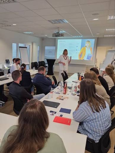 Ulrike Dolle im KI Workshop für Ausbilderinnen und Ausbilder mit Teilnehmenden am Tisch